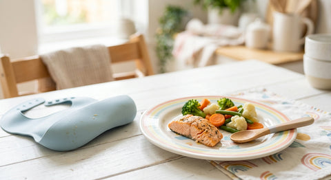 Filet de saumon cuit émietté avec légumes dans une assiette de bébé, repas riche en oméga-3