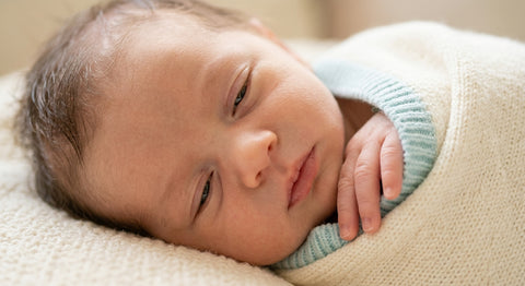 Gros plan d'un bébé endormi avec les paupières mi-closes, signe de lagophtalmie nocturne