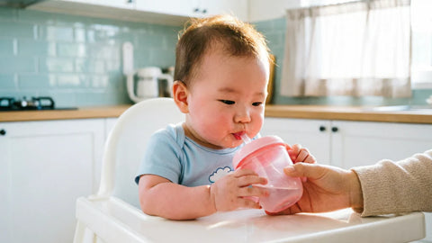 Bébé de 6 mois buvant de l eau dans un gobelet à bec adapté tenu par sa mère | Securidou