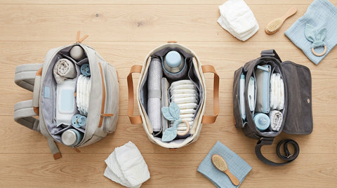 Comparatif trois sacs à langer : sac à dos, cabas et bandoulière ouverts sur une surface en bois avec accents | Securidou