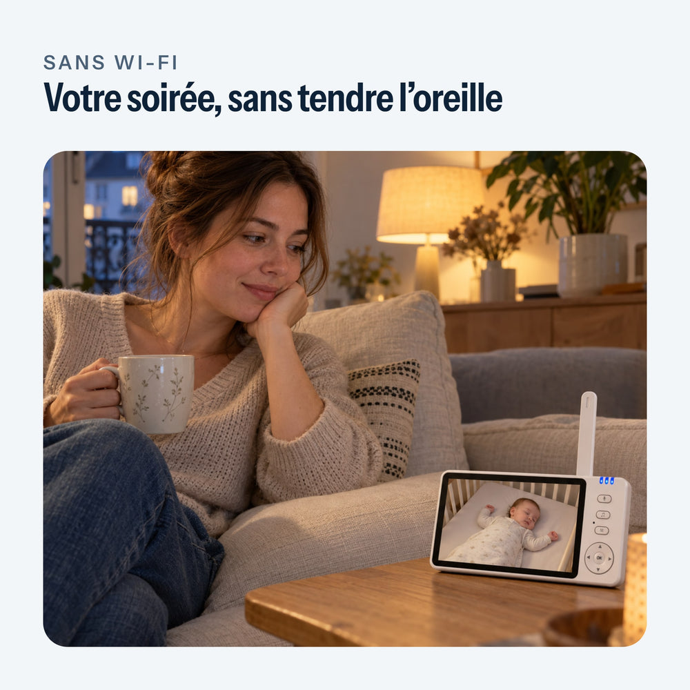 Babyphone à écran posé sur la table basse du salon, le soir