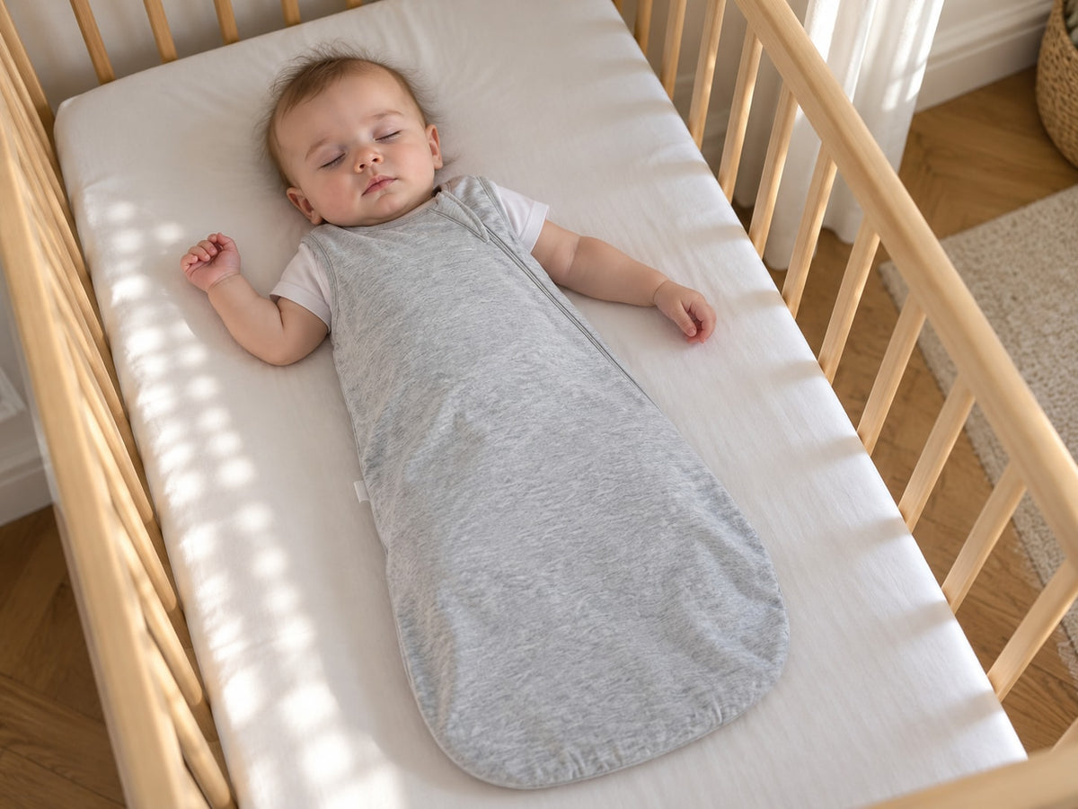 Bébé endormi sur le dos dans un lit vide, couvert par la gigoteuse Securidou
