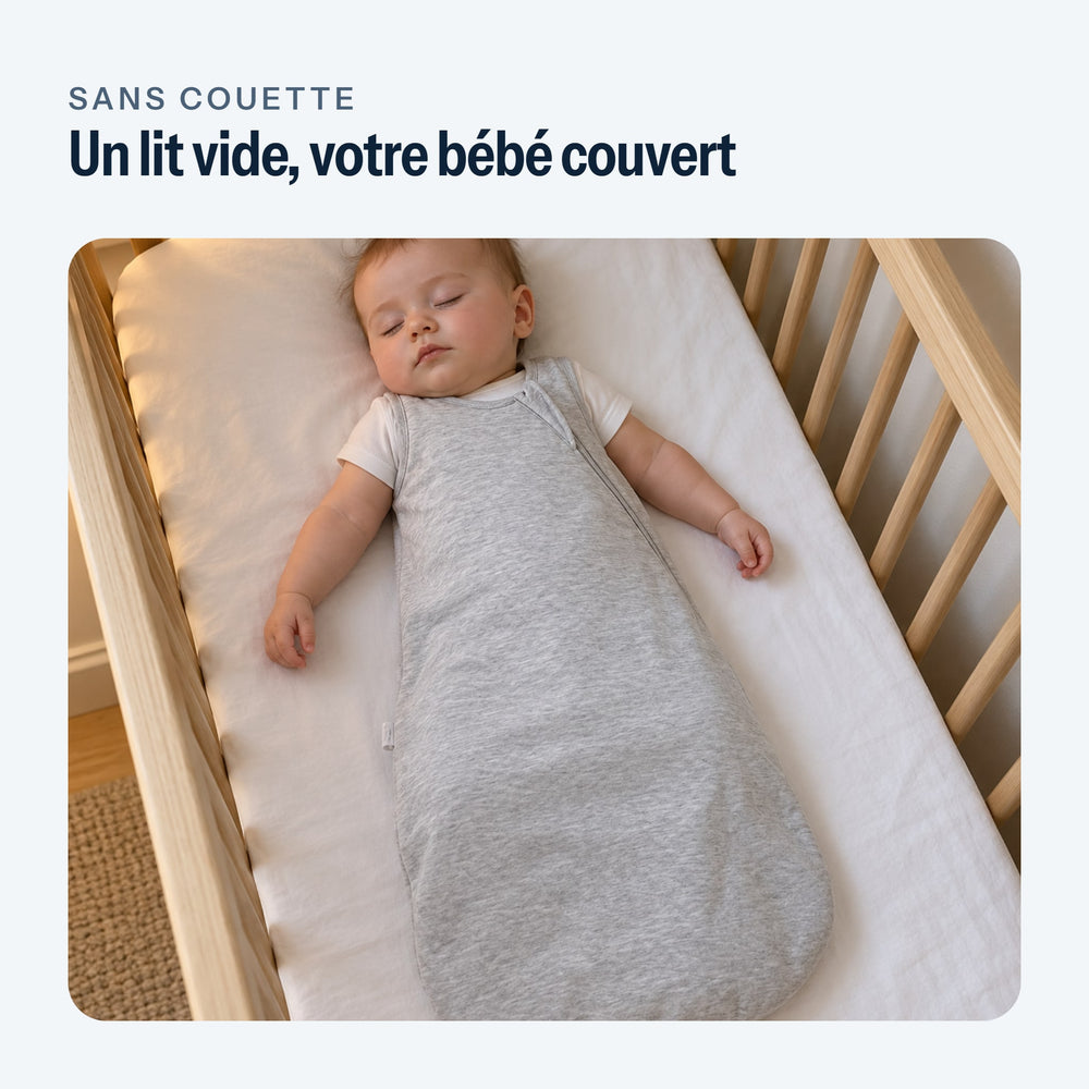 Bébé endormi sur le dos dans la gigoteuse grise, dans un lit vide