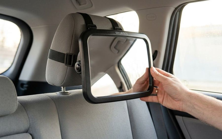 Main qui oriente le miroir sur sa rotule, fixé sur l’appui-tête arrière