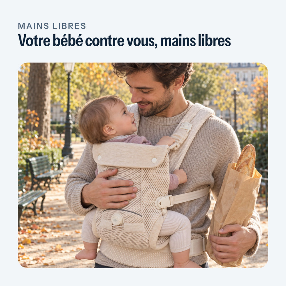 Père en promenade, son bébé face à lui dans le porte-bébé beige, une main sur son dos