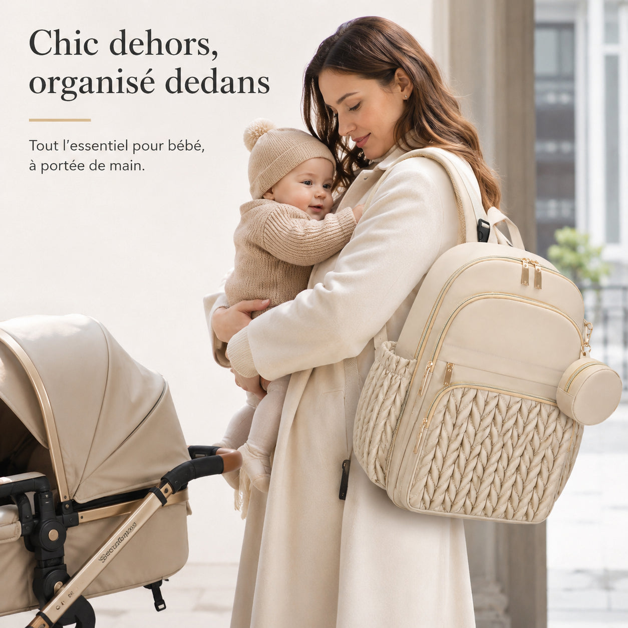Maman portant le sac à dos à langer Securidou beige en sortie, son bébé dans les bras près de la poussette