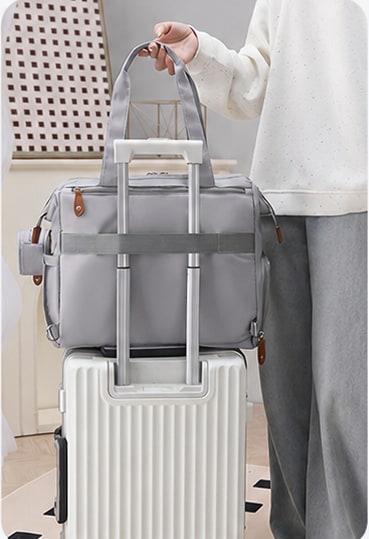 Sac à langer Securidou fixé sur la poignée d’une valise
