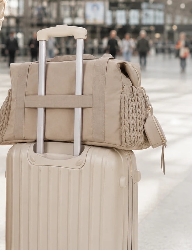 Sac de maternité Securidou enfilé sur la poignée d’une valise, dans une gare