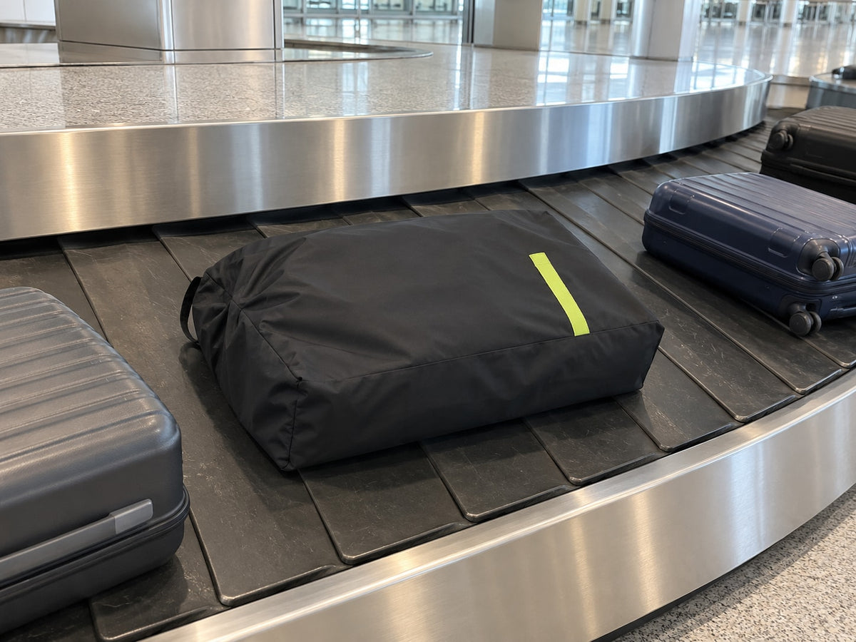 Poussette fermée dans le sac de transport Securidou sur un tapis à bagages